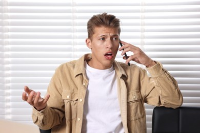 Photo of Young man complaining to someone via phone indoors