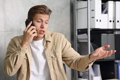 Photo of Young man complaining to someone via phone indoors