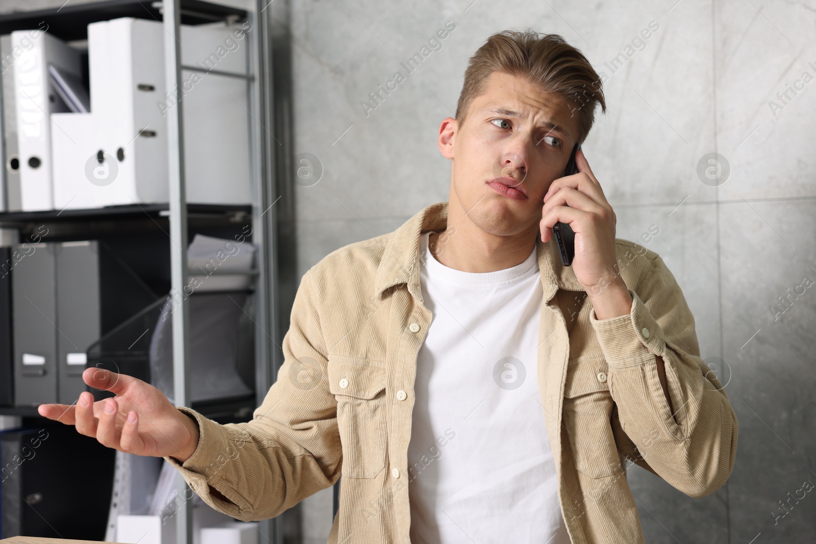 Photo of Young man complaining to someone via phone indoors