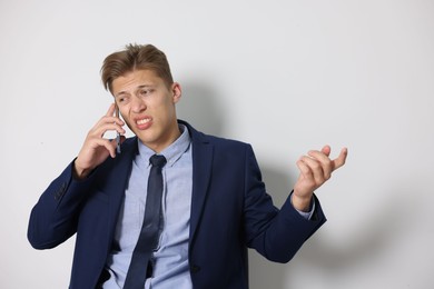 Photo of Young businessman complaining to someone via phone indoors