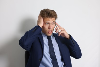 Photo of Young businessman complaining to someone via phone indoors