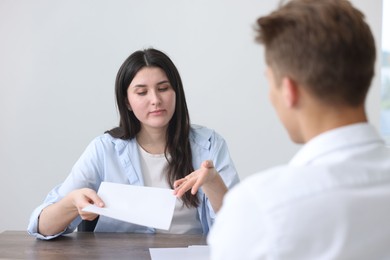 Photo of Young woman complaining to man at wooden table indoors