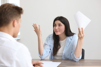 Photo of Young woman complaining to man at wooden table indoors