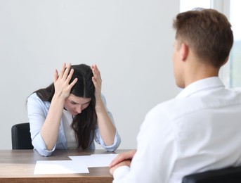 Photo of Young woman complaining to man at wooden table indoors