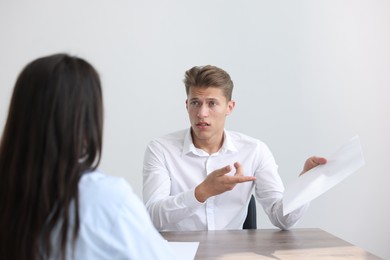 Photo of Young man complaining to woman at wooden table indoors