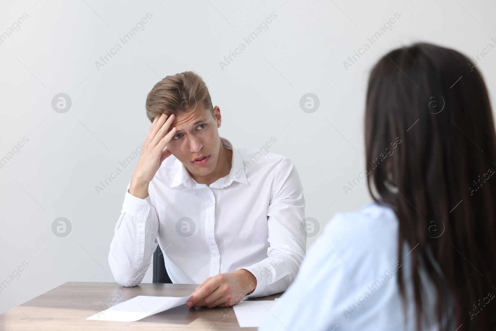 Photo of Young man complaining to woman at wooden table indoors