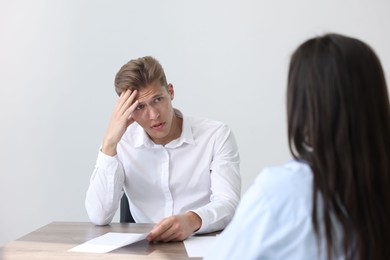 Photo of Young man complaining to woman at wooden table indoors