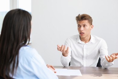 Photo of Young man complaining to woman at wooden table indoors