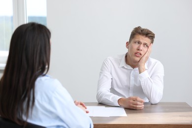 Photo of Young man complaining to woman at wooden table indoors