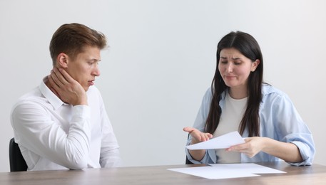Photo of Young woman complaining to man at wooden table indoors
