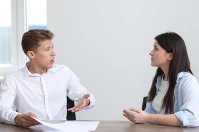 Photo of Young woman complaining to man at wooden table indoors