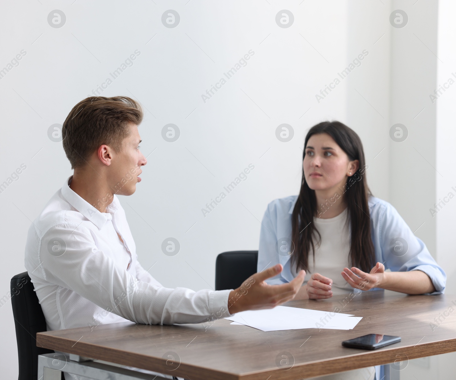 Photo of Young woman complaining to man at wooden table indoors