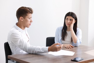 Photo of Young man complaining to woman at wooden table indoors