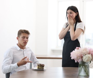 Photo of Young man complaining to waiter about cake at table in restaurant
