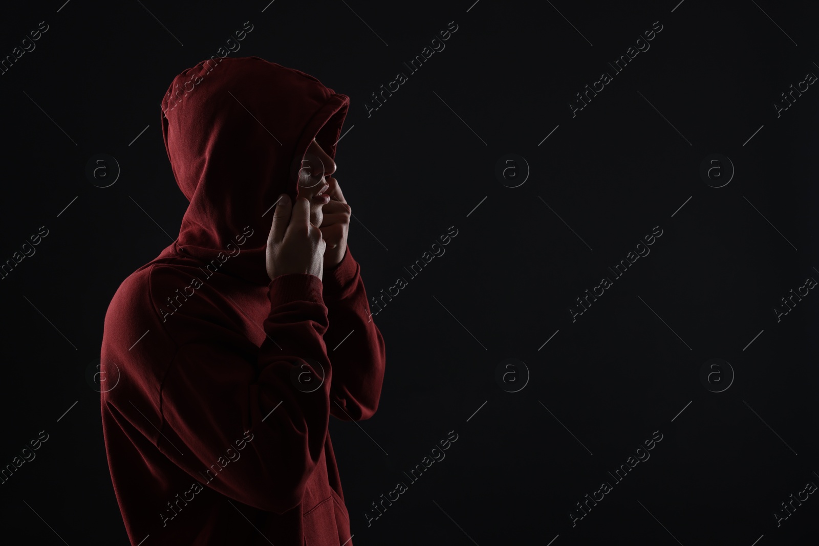 Photo of Anonymity. Man hiding his face in darkness, space for text