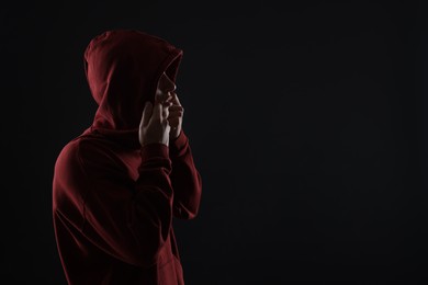 Photo of Anonymity. Man hiding his face in darkness, space for text