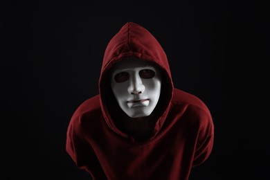 Photo of Anonymity. Man wearing mask on dark background