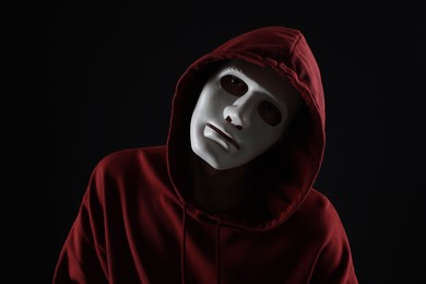 Photo of Anonymity. Man wearing mask on dark background