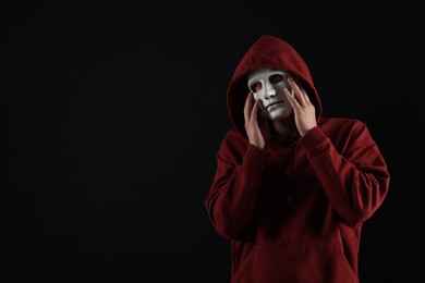 Photo of Anonymity. Man wearing mask on dark background, space for text