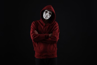 Photo of Anonymity. Man wearing mask on dark background