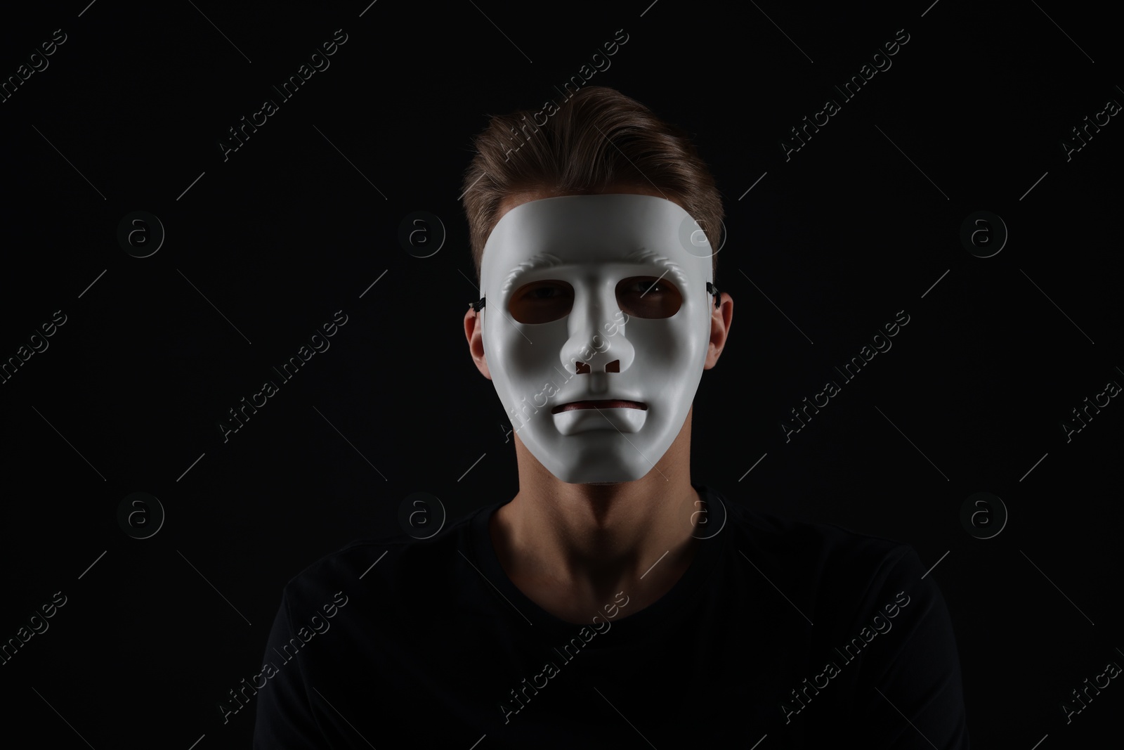 Photo of Anonymity. Man wearing mask on dark background