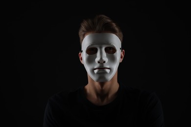 Photo of Anonymity. Man wearing mask on dark background