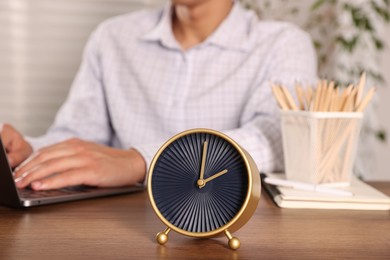 Photo of Deadline. Alarm clock and man working on laptop at wooden table, selective focus
