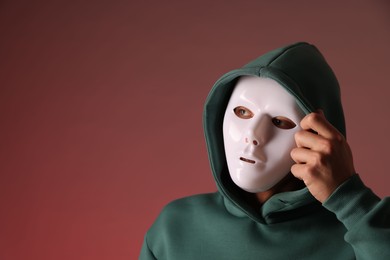 Photo of Anonymity. Man wearing mask on red background, space for text