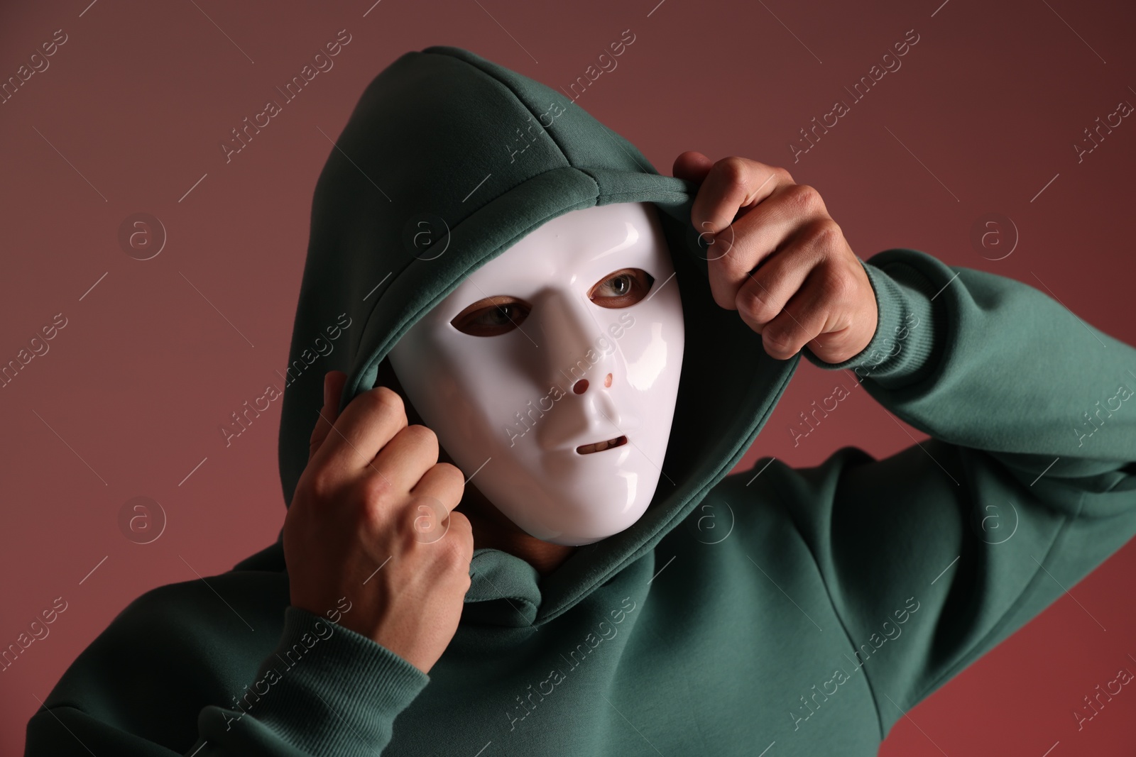 Photo of Anonymity. Man wearing mask on red background