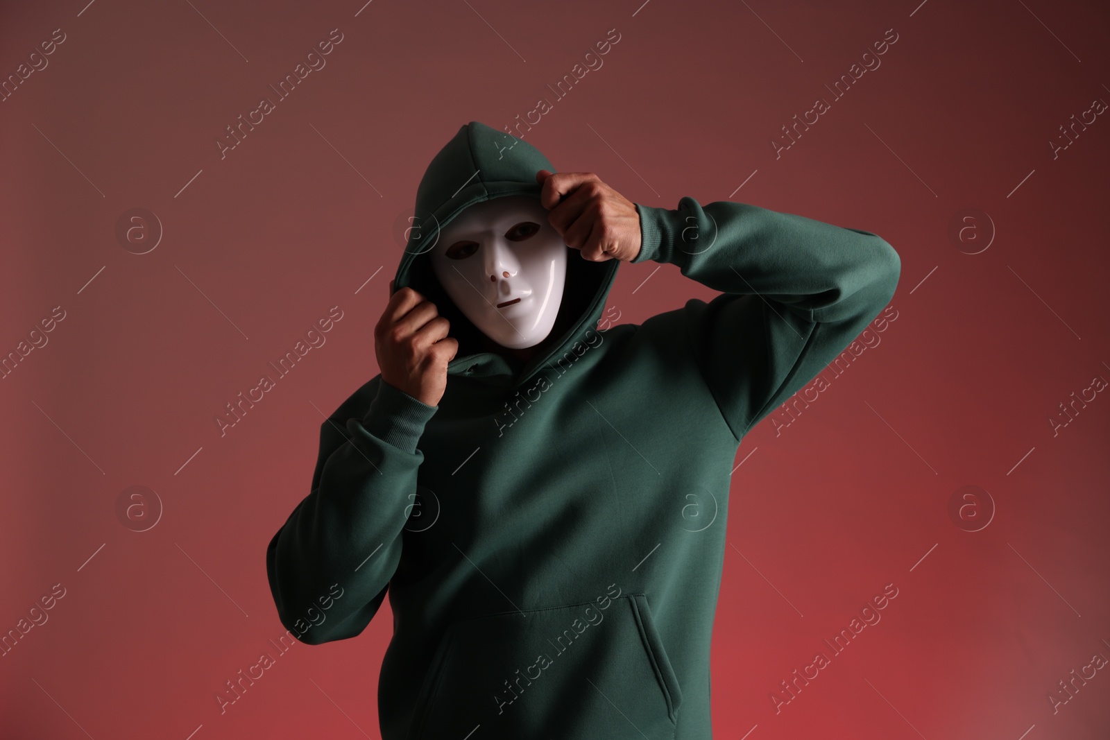 Photo of Anonymity. Man wearing mask on red background
