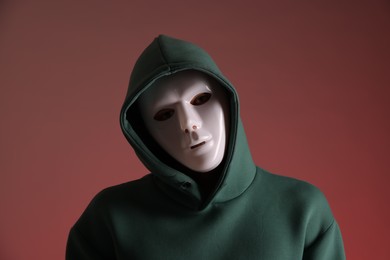 Photo of Anonymity. Man wearing mask on red background