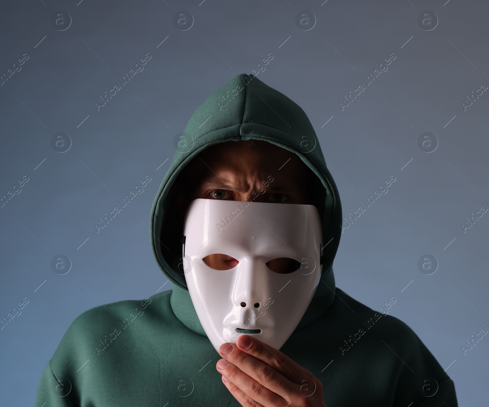 Photo of Anonymity. Man wearing mask on grey background