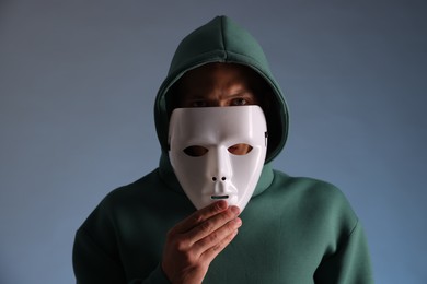 Photo of Anonymity. Man wearing mask on grey background