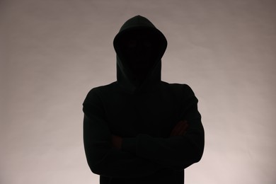 Photo of Silhouette of anonymous man in hood on grey background