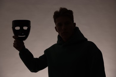 Photo of Anonymity. Silhouette of man with mask on grey background
