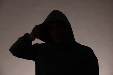 Photo of Silhouette of anonymous man in hood on grey background