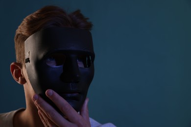 Photo of Anonymity. Man wearing mask on blue background, space for text