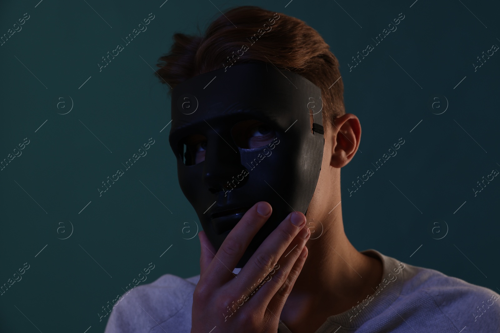 Photo of Anonymity. Man wearing mask on blue background