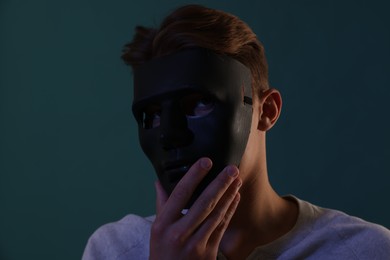 Photo of Anonymity. Man wearing mask on blue background