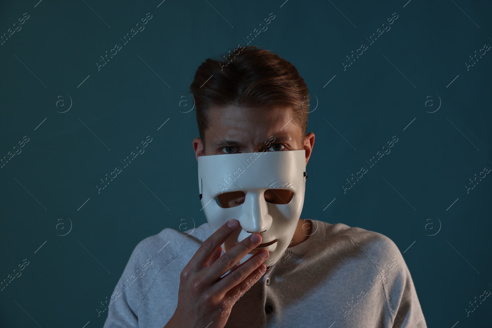 Photo of Anonymity. Man wearing mask on blue background