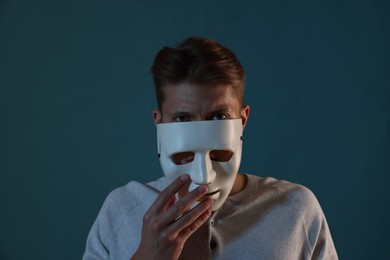 Photo of Anonymity. Man wearing mask on blue background