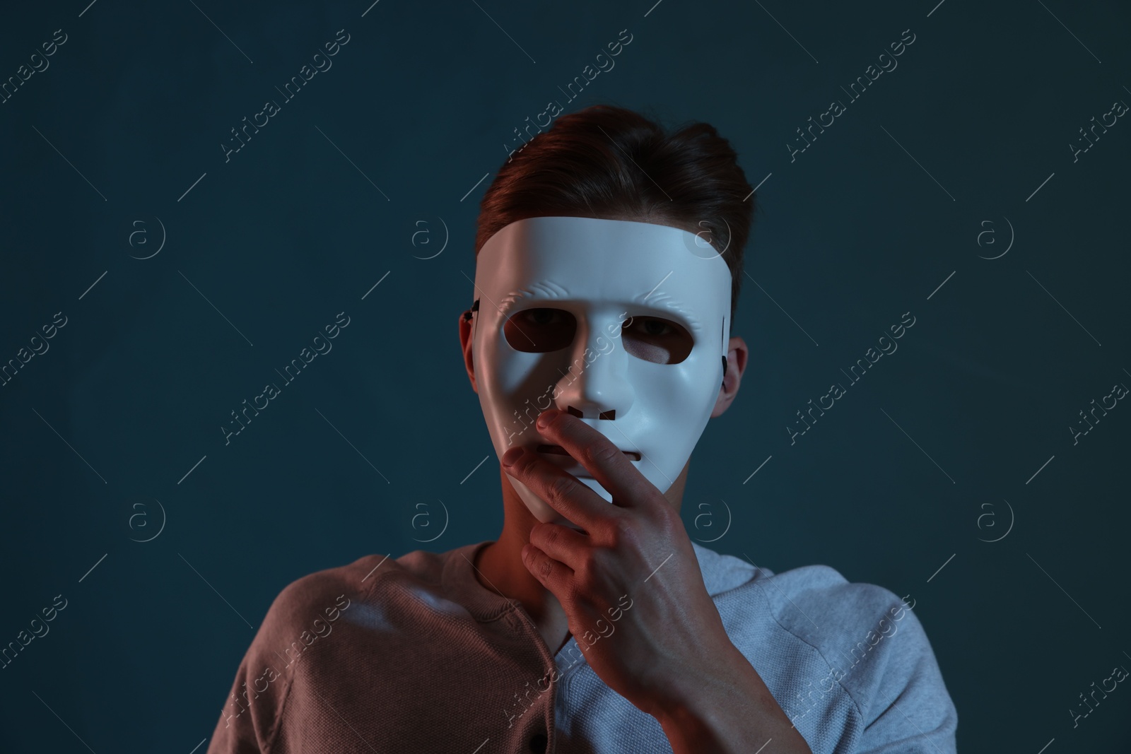 Photo of Anonymity. Man wearing mask on blue background