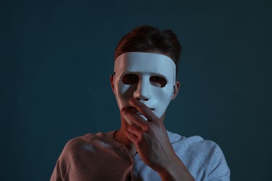 Photo of Anonymity. Man wearing mask on blue background