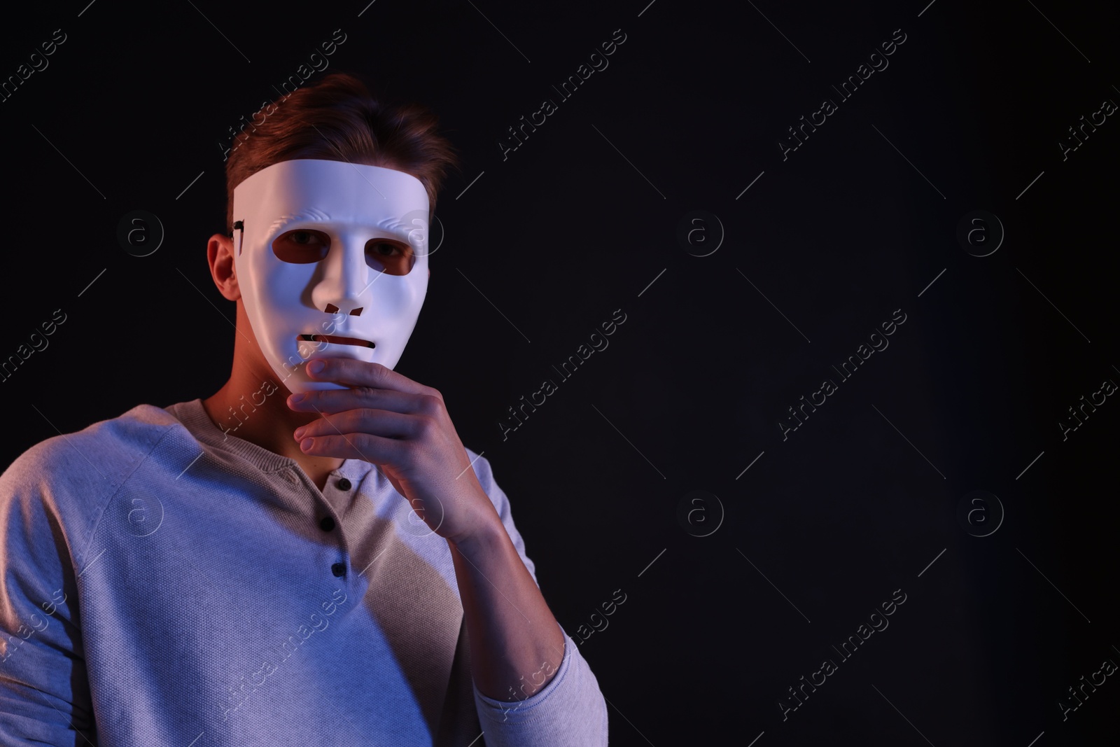 Photo of Anonymity. Man wearing mask on black background, space for text