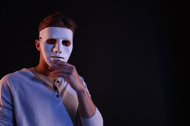 Photo of Anonymity. Man wearing mask on black background, space for text