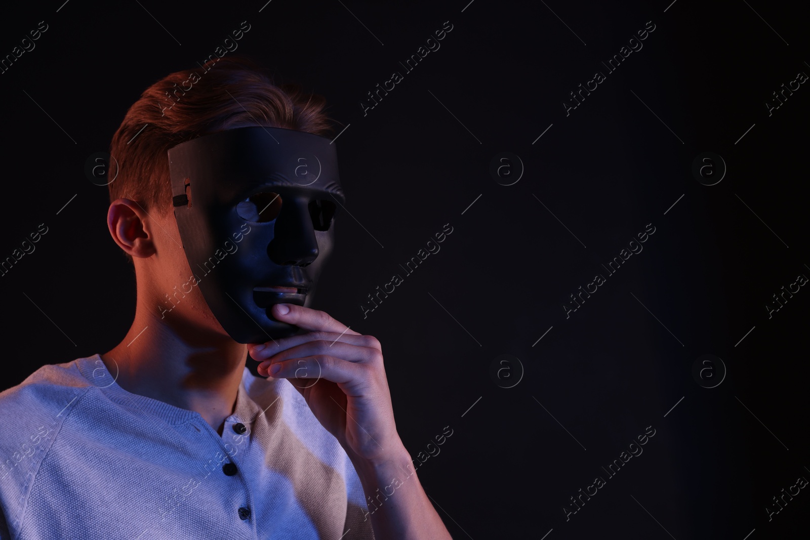 Photo of Anonymity. Man wearing mask on black background, space for text