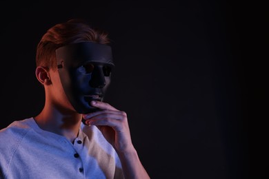 Photo of Anonymity. Man wearing mask on black background, space for text