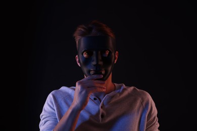 Photo of Anonymity. Man wearing mask on black background