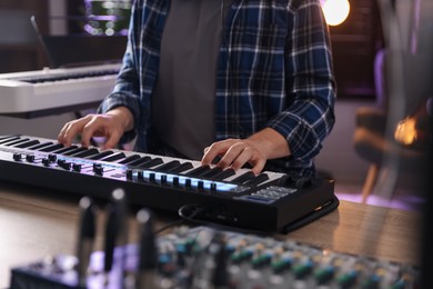 Photo of Man working with MIDI keyboard at table, closeup