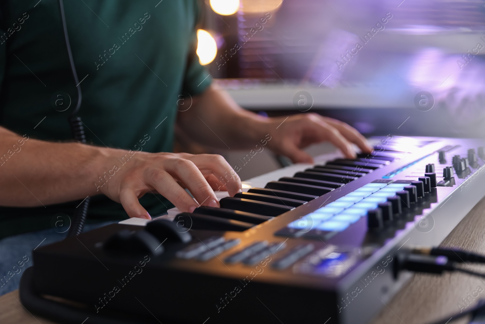 Photo of Man working with MIDI keyboard at table indoors, closeup